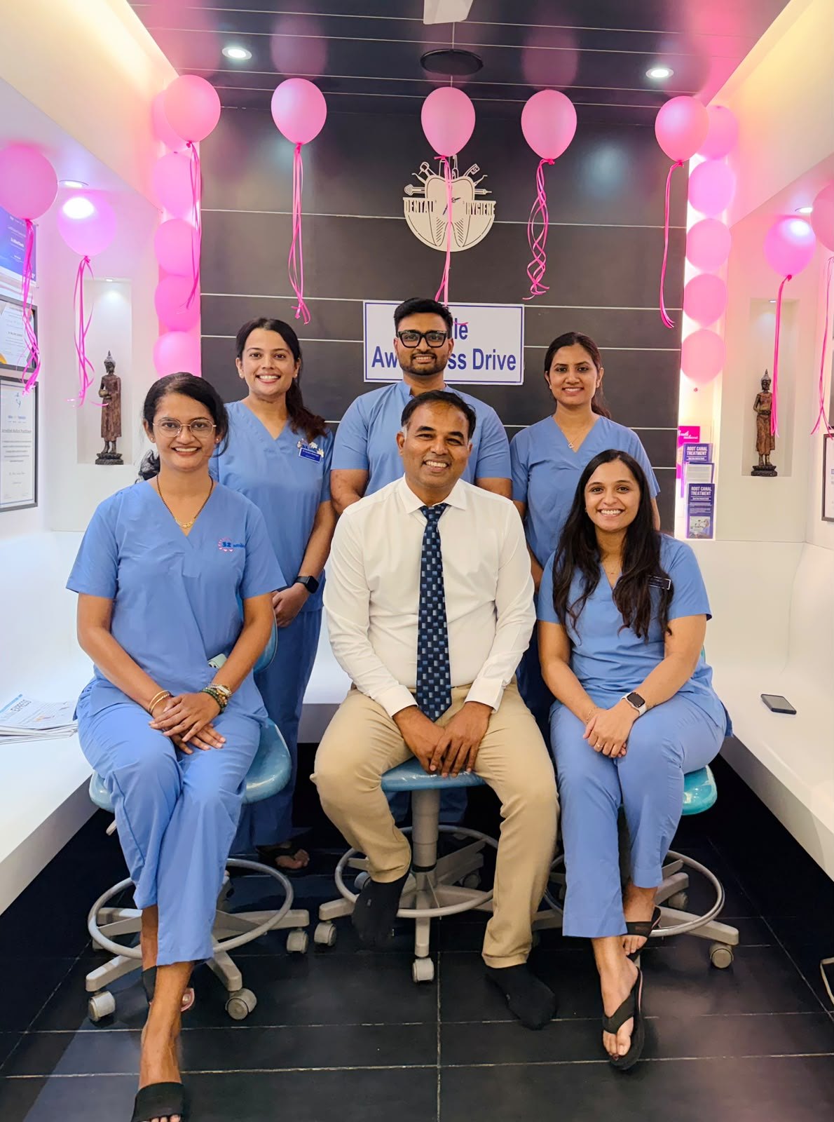Dr. Milind Darda seated with five members of the 32 Smiles team in blue scrubs